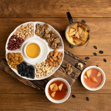 Düz yerde yemek vardı. Besleyici atıştırmalık ya da aperatif. Bir tabak fındık ve ortasında bal olan kurutulmuş meyve. Çaydanlık ve fincanlar, ahşap masa arkasında meyve çayı. Yumuşak odak