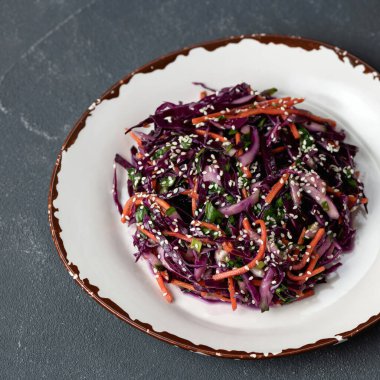 Kil tabakta taze sebze ve sebzeleri karıştırdım. Üst Manzara. Kırmızı lahana, havuç, pamuk, şifalı ot ve susam tohumundan oluşan vitamin salatası. Gri arka planda vejetaryen yemeği. Sağlıklı yiyecekler. Yumuşak odak