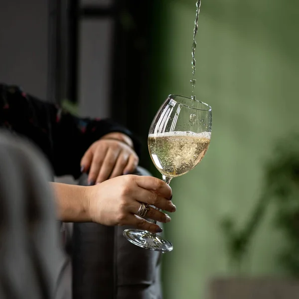 Женские руки заменяют бокал вина под струей белого вина. Расслабляющая женская идея. Крупный план — стоковое фото