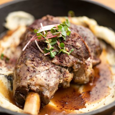 Kızarmış bacak ya da kemiğe et konmuş ve üstünde mikroçerez var. Bulanık arka planda pişirilmiş yemek ve sos. Yakın çekim. Yumuşak odaklanma. Kare biçimi