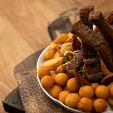 Bira çerezi. Patates kroketleri, kızarmış ekmekler ve ahşap arka planda kızarmış patatesler. Besleyici atıştırmalık ya da aperatif. Yumuşak odaklanma. Soası sol tarafa kopyala