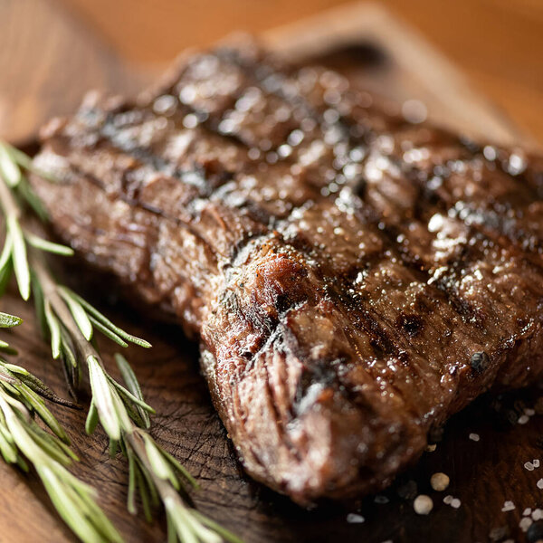 Grilled meat with sprig of rosemary. Cooked dish, juicy fillet on blurred background. Soft focus. Close up shot.