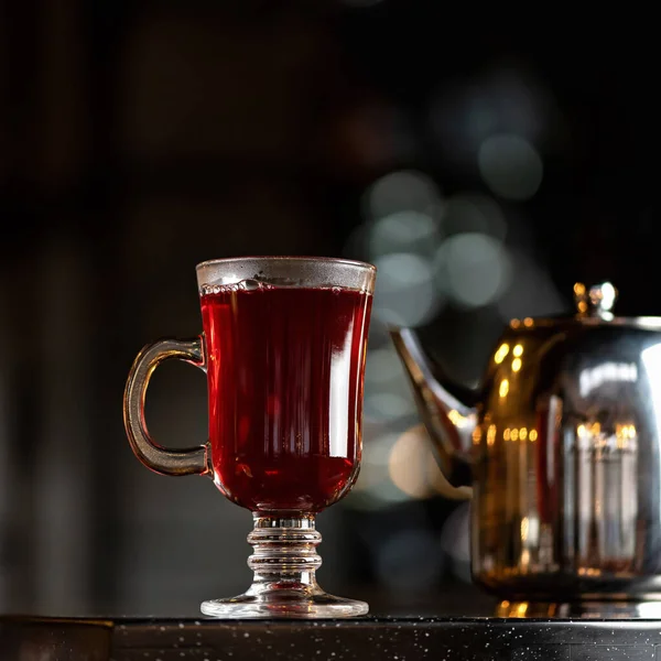 Schwarzer Tee in Glasschale vorhanden. Erfrischendes natürliches Getränk oder Getränk. Hohe Tasse voller Tee hinterleuchtet auf verschwommenem Hintergrund mit Kopierraum am oberen Bildrand — Stockfoto