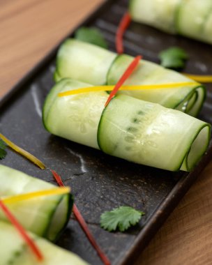 Taze salatalık, vejetaryen aperatifi. Siyah tabakta nefis sebze tabağı. Sağlıklı yiyecekler. Bahar vitamini atıştırması. Yumuşak odaklanma. Dikey format. Yakın çekim.