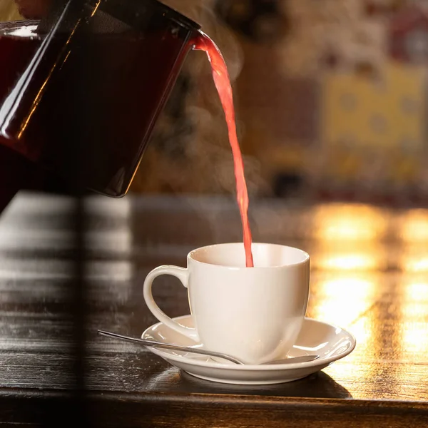 Red Hot Tea strömt in weiße Tasse auf hinterleuchtetem, verschwommenem Hintergrund. Konzept der Teezeremonie. Morgen Tasse Tee. Seitenansicht. Weicher Fokus. Kopierraum — Stockfoto