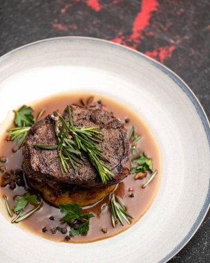 Lüks yemekler. Kızarmış ya da ızgara biftekli tabak. Domates soslu biberiyeli dana eti madalyonu. Üst Manzara. Dikey format. Yumuşak odaklanma. Yakın çekim.