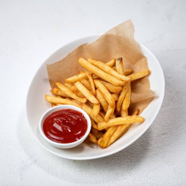 Domates soslu kızarmış patates, ketçaplı patates kızartması. Gıda tabakası beyaz arka planda izole