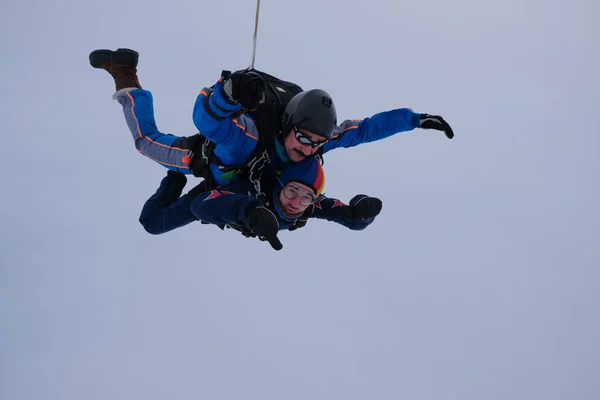 Skydiving. Tandem jump. Two men are flying in the cloudy sky.