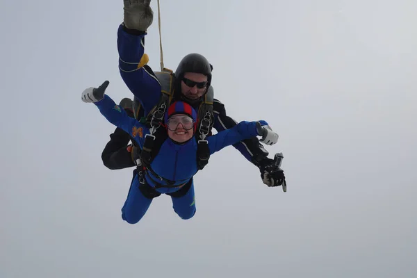 Skydiving. Tandem jump. A young woman and her instructor are in the sky.