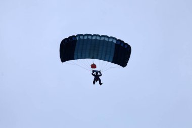 Hava dalışı. İniş. Bir paraşütçü paraşütü uçuruyor ve yere iniyor..