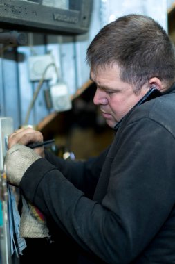 İş yerinde cep telefonuyla konuşan erkek işçinin yakın plan portresi.