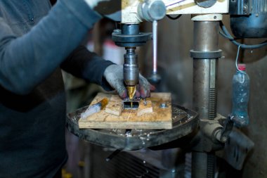 Bir işçi sondaj makinesinin bir parçasını deliyor.