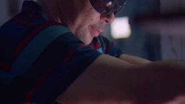 Kesici, plazma meşalesi ile kalın çelik boşluklarını kesiyor. Kırık metal damlaları farklı yönlere saçılıyor. 