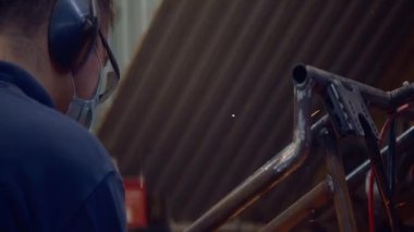 Öğütücü tıbbi bir maskenin dikişlerini öğütücüyle temizliyor. Koronavirüs enfeksiyonu ihtimaline karşı kendini izole etme kurallarına uyuyor. 