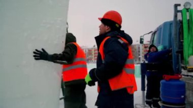 Birleştiriciler vinç kullanarak bir arabadan buz panelleri indirir. 