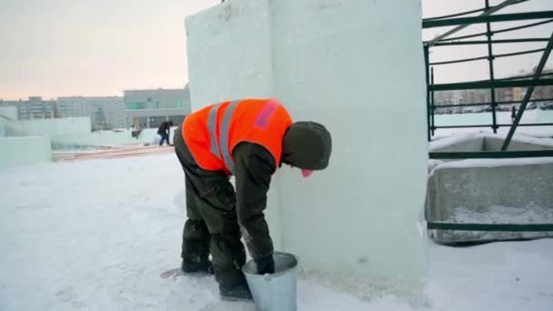 Instalatér Staveništi Ledového Města Pokrývá Spoje Ledových Panelů Mokrým Sněhem — Stock video