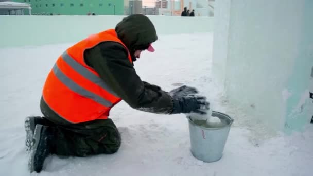 Instalatér Staveništi Ledového Města Pokrývá Spoje Ledových Panelů Mokrým Sněhem — Stock video