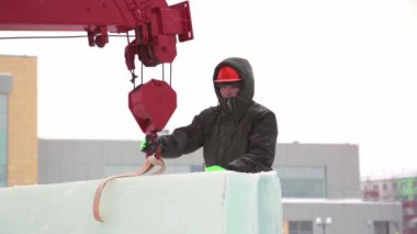 Ceketli ve kasklı bir askıcı kancaya kablo takar.