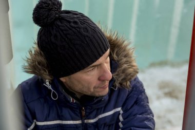 Ceketli ve siyah şapkalı işçi derleyicisi buz bloklarını boşaltıyor