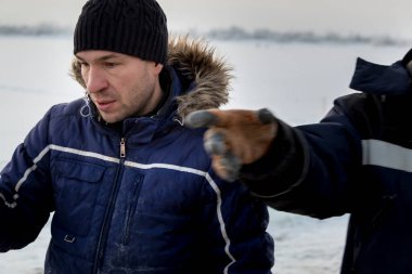 Ceketli ve siyah şapkalı işçi derleyicisi buz bloklarını boşaltıyor