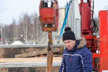 Ceketli ve siyah şapkalı işçi derleyicisi buz bloklarını boşaltıyor