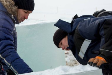 Birleştiriciler vinç kullanarak bir arabadan buz panelleri indirir.