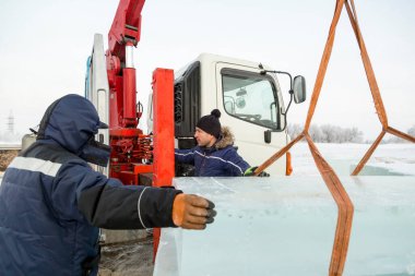 Birleştiriciler vinç kullanarak bir arabadan buz panelleri indirir.