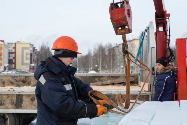 Birleştiriciler vinç kullanarak bir arabadan buz panelleri indirir.