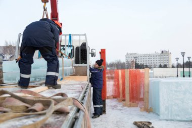 Birleştiriciler vinç kullanarak bir arabadan buz panelleri indirir.