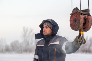 Kancadaki mavi ceketli bir tesisatçının portresi.