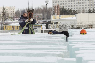Birleştiriciler vinç kullanarak bir arabadan buz panelleri indirir.