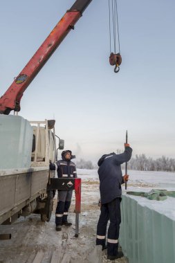 Bir işçi buz kalıplarını levyeyle itiyor.