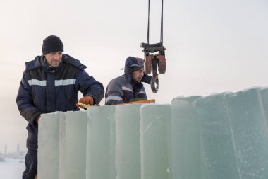 Kurucular buz panellerini vinç kullanarak arabaya yüklerler.