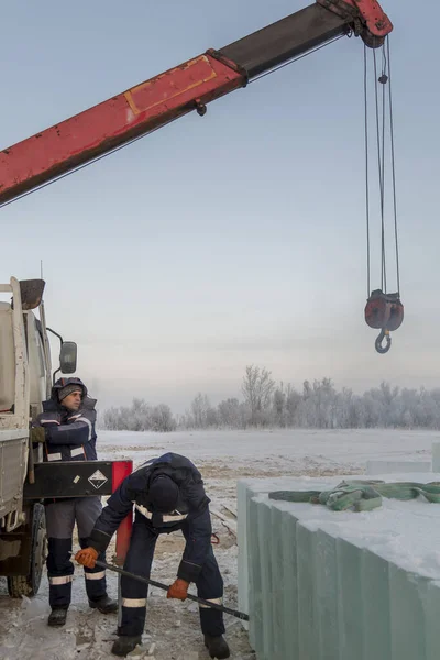 A worker pushes the ice blocks apart with a crowbar