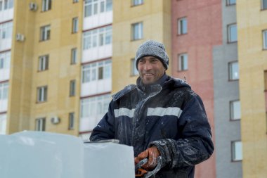 Mavi ceketli ve buz panelinin yanında örülmüş siyah şapkalı bir montajcının portresi.