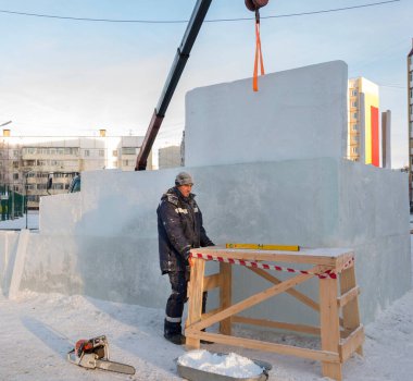 Kışın işçi bir derleyici ahşap bir yapıyı sürüklüyor.