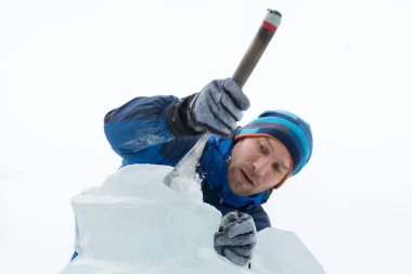 Heykeltıraş Noel için buz kalıbından bir buz heykeli kesiyor.