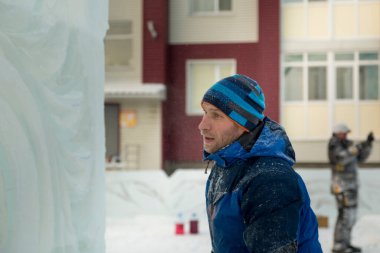 Mavi tulumlu bir ustanın portresi. Buz panelinde elinde bir işaret var.