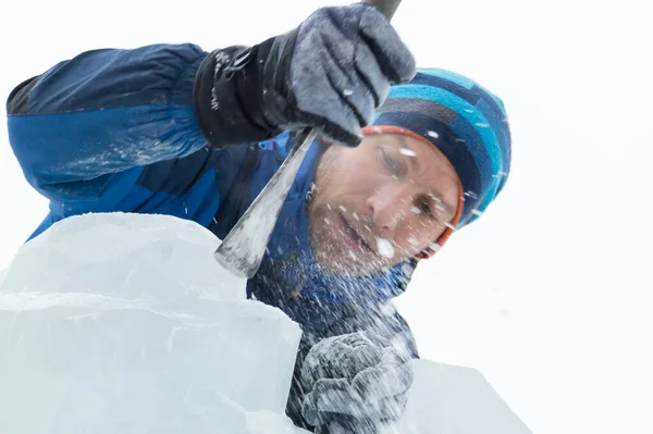 The sculptor cuts an ice figure out of a block of ice for Christmas