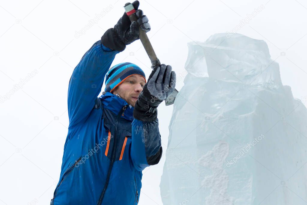 The sculptor cuts an ice figure out of a block of ice for Christmas