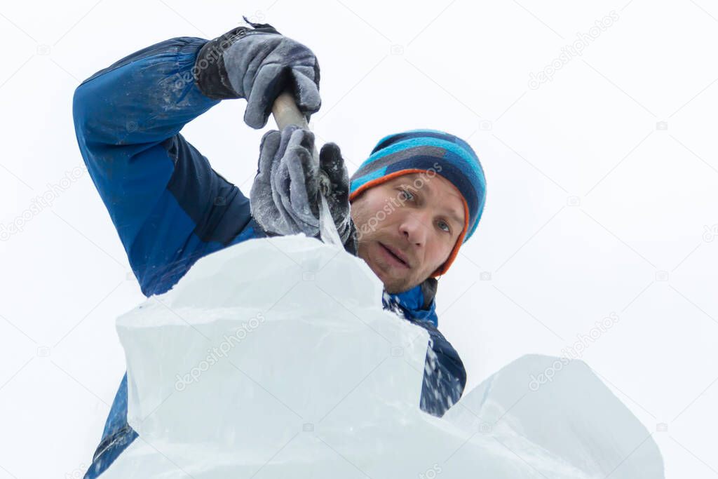 The sculptor cuts an ice figure out of a block of ice for Christmas