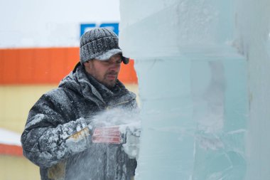 Heykeltıraş, buzdan bir buz figürünü Noel için elektrikli testere ile kesiyor.