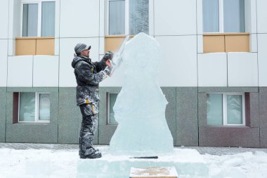 Heykeltıraş, buzdan bir buz figürünü Noel için elektrikli testere ile kesiyor.