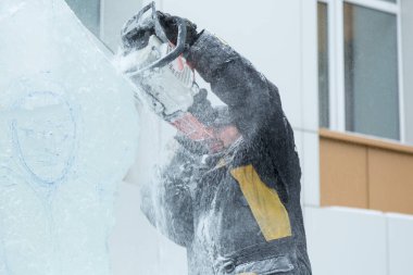 Heykeltıraş, buzdan bir buz figürünü Noel için elektrikli testere ile kesiyor.