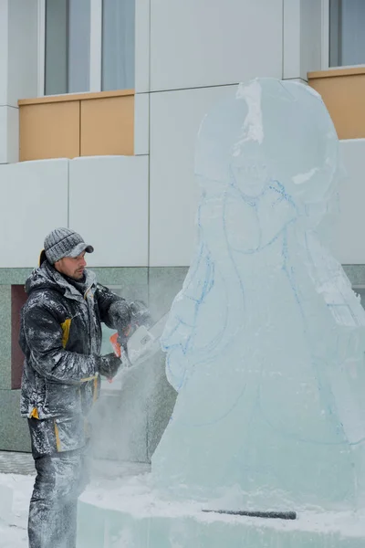 Sochař vyřízne postavu z ledového špalku motorovou pilou — Stock fotografie