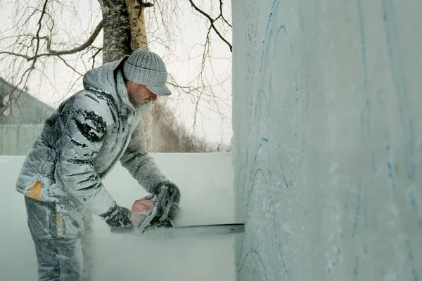 Le sculpteur découpe une figure d'un bloc de glace avec une scie à essence — Photo