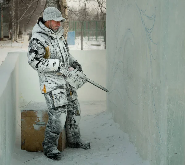 El escultor corta una figura de un bloque de hielo con una sierra de gasolina — Foto de Stock