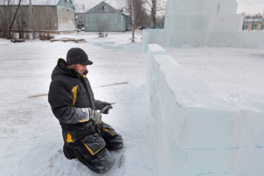Heykeltıraş buz kalıbından bir buz kalıbını kesiyor.