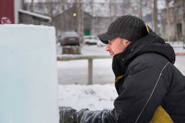 The sculptor cuts an ice figure out of an ice block with a chisel