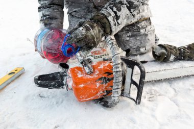 Kışın çalışan bir işçi dışarıdaki elektrikli testereyi tamir eder.